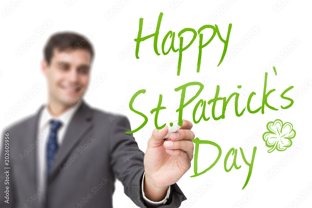 Young businessman writing something against shamrock