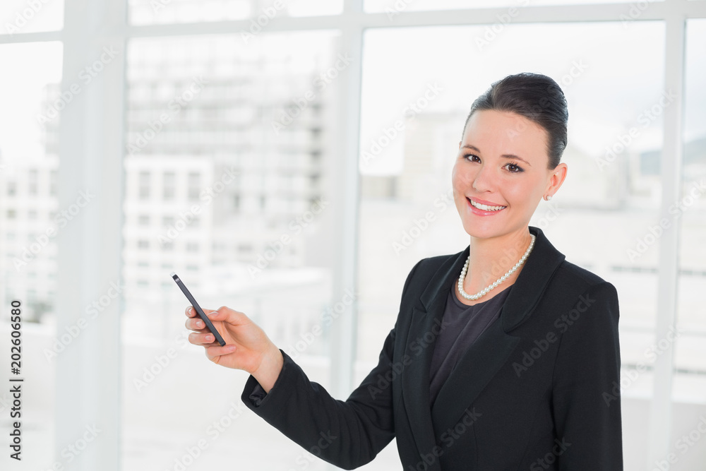 Smiling young elegant businesswoman looking at cellphone