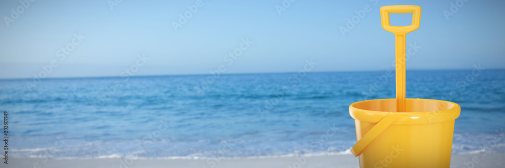 Yellow bucket and shovel against beach against clear sky Yellow bucket and shovel against beach against clear sky