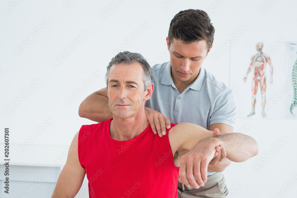 Male physiotherapist stretching a mature mans arm Male physiotherapist stretching a mature mans arm
