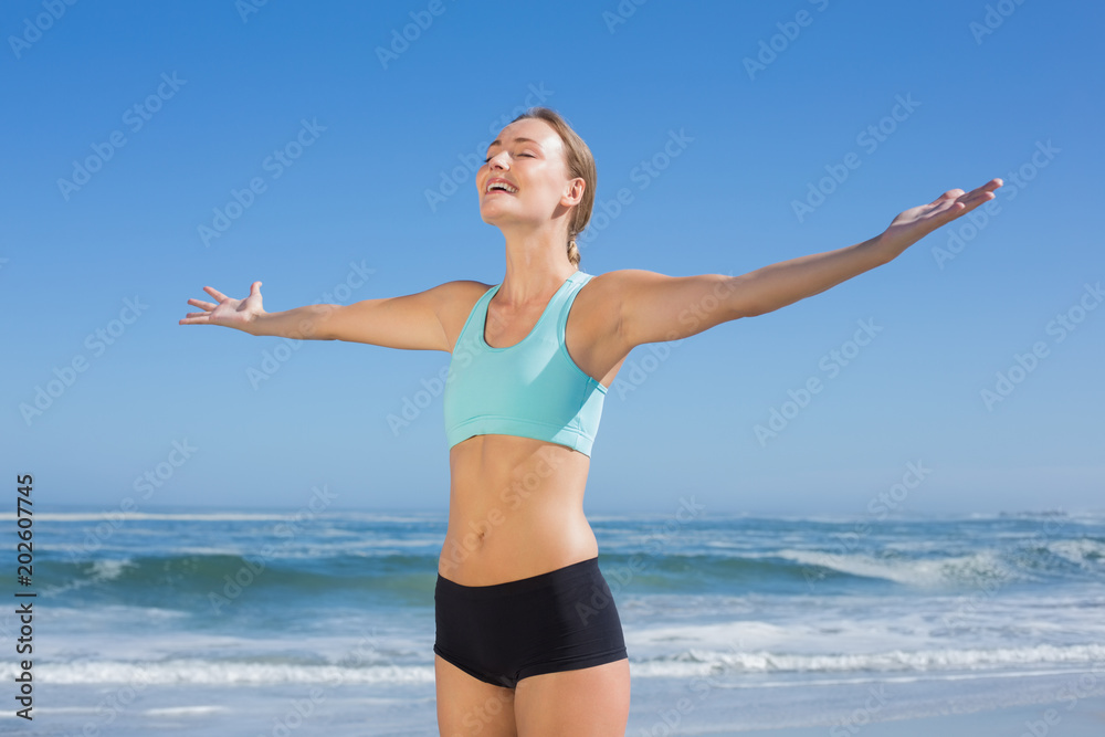 Fit woman standing on the beach with arms out Fit woman standing on the beach with arms out