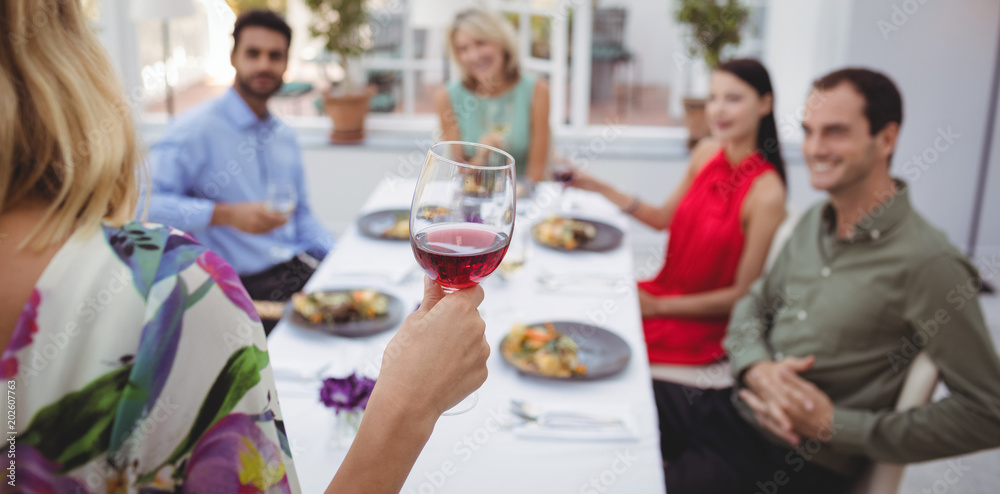 Group of friends interacting with each other while having meal together Group of friends interacting with each other while having meal together