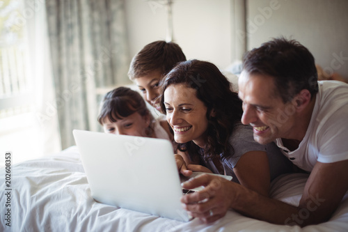 Happy family using laptop on bed in bedroom