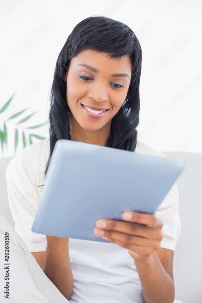 Thoughtful black haired woman in white clothes using a tablet pc Thoughtful black haired woman in white clothes using a tablet pc