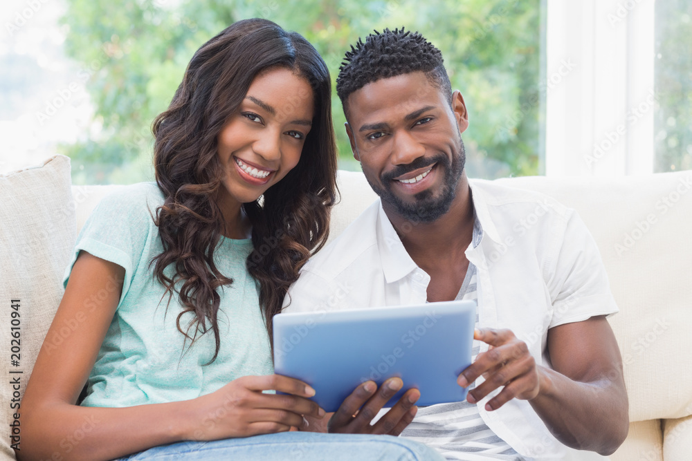 Happy couple using tablet together on the couch Happy couple using tablet together on the couch