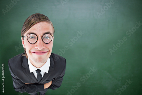 Geeky businessman smiling at camera  against green chalkboard
