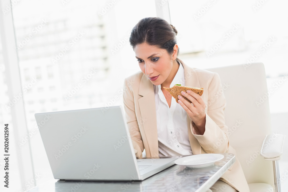 Focused businesswoman eating lunch as she is working Focused businesswoman eating lunch as she is working