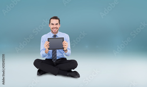 Smiling businessman showing his digital tablet against blue vignette background