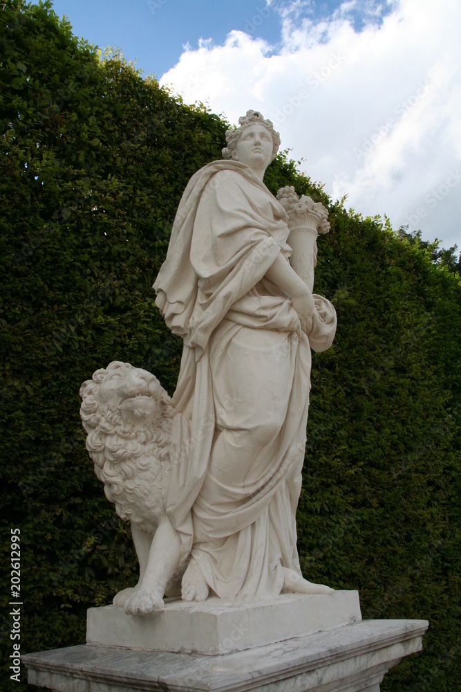 White marble statue of Eath in Versailles garden in bright summer day