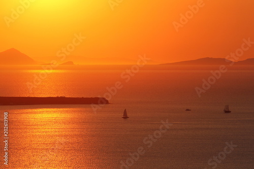 Sunset in orange color on the sea near Santorini island