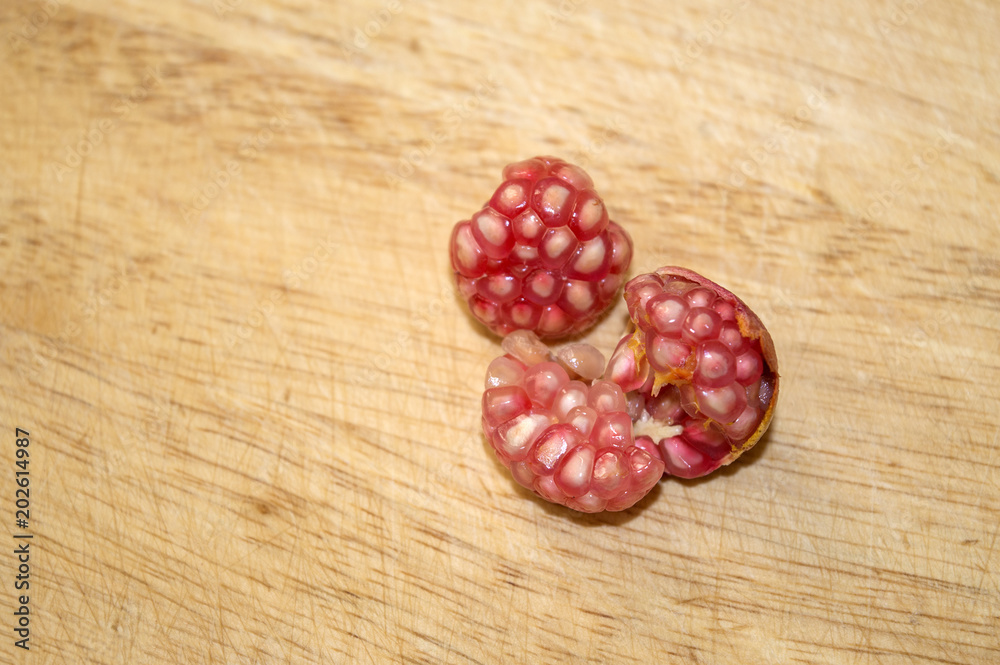 Φωτογραφία Peeled dwarf pomegranate fruits on wooden surface close up, crop of punica granatum var