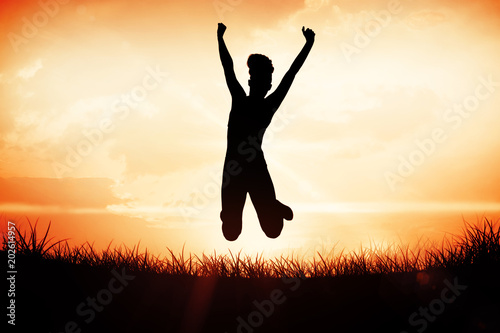 Sporty happy blonde jumping against orange sunrise
