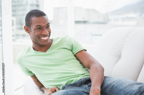 Smiling relaxed Afro man sitting on sofa