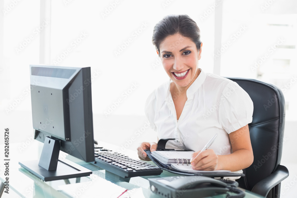 Happy businesswoman arranging her diary at her desk Happy businesswoman arranging her diary at her desk