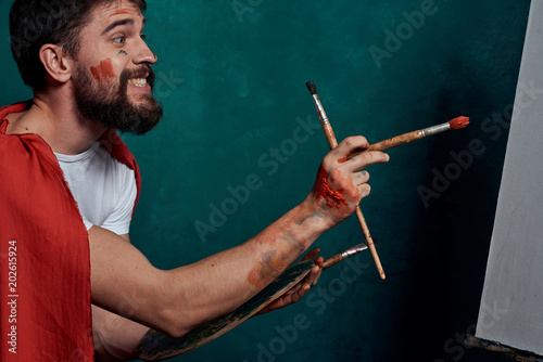 artist smeared with paint with a brush in hand red fabric on the shoulder