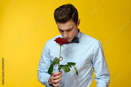 elegant man holding a flower in his hand and tilted his head