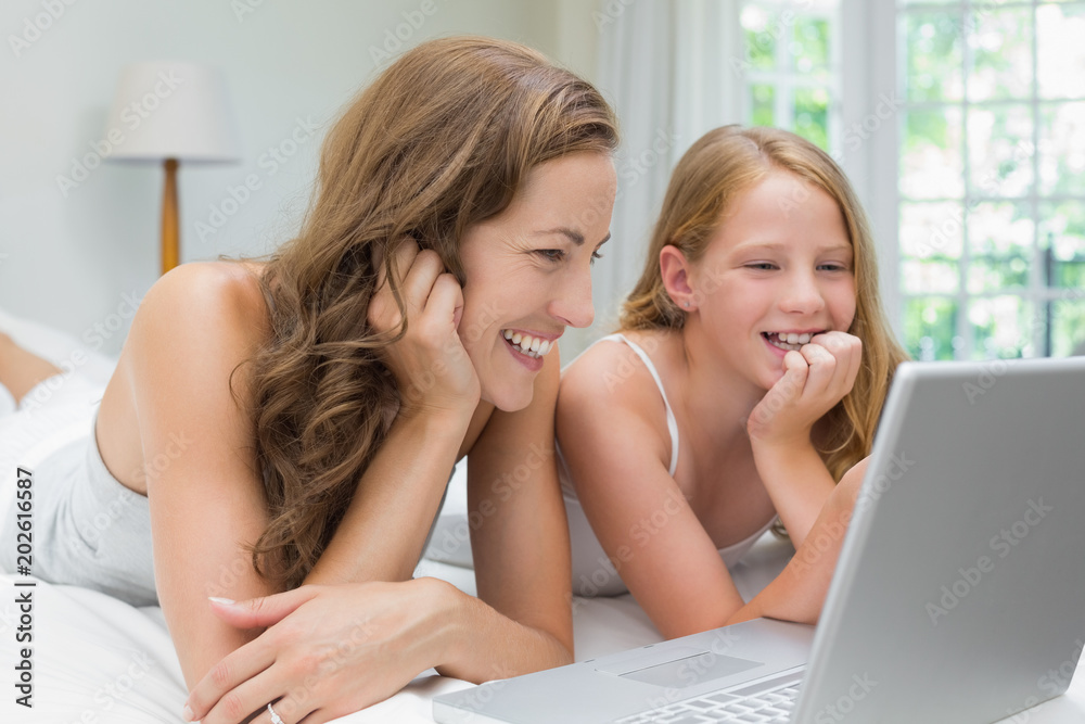 Happy mother and daughter using laptop in bed Happy mother and daughter using laptop in bed