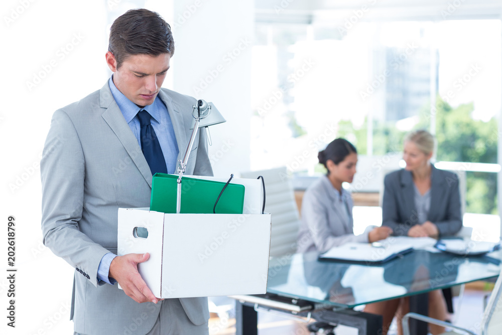 Businessman carrying his belongings in box Businessman carrying his belongings in box