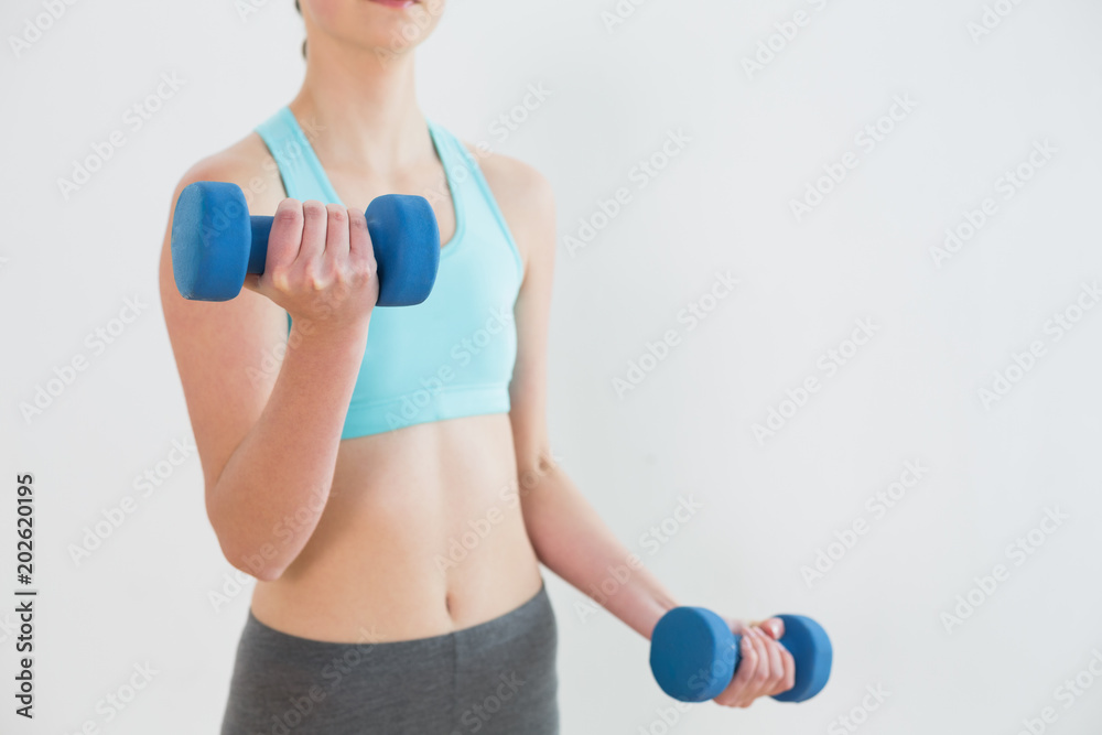Close up mid section of woman with dumbbells Close up mid section of woman with dumbbells
