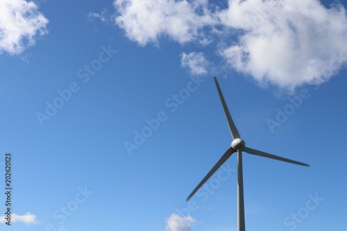 Wind tturbines against blue sky with fluffy white clouds © mcKensa