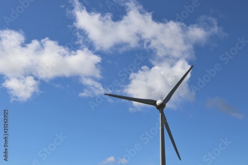 Wind tturbines against blue sky with fluffy white clouds © mcKensa