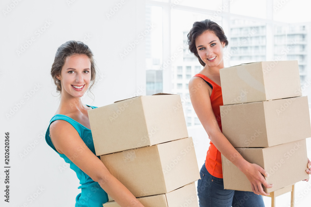 Female friends carrying boxes in in new house Female friends carrying boxes in in new house