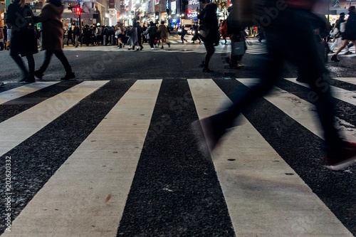 忙しない夜のスクランブル交差点を行きかう人々の足元と横断歩道