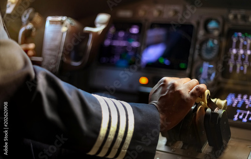 Billede på lærred Cropped Hands of African Pilot flying a commercial airplane, cockpit view close