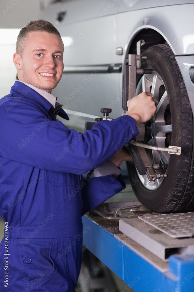 Smiling mechanic changing a car wheel Smiling mechanic changing a car wheel