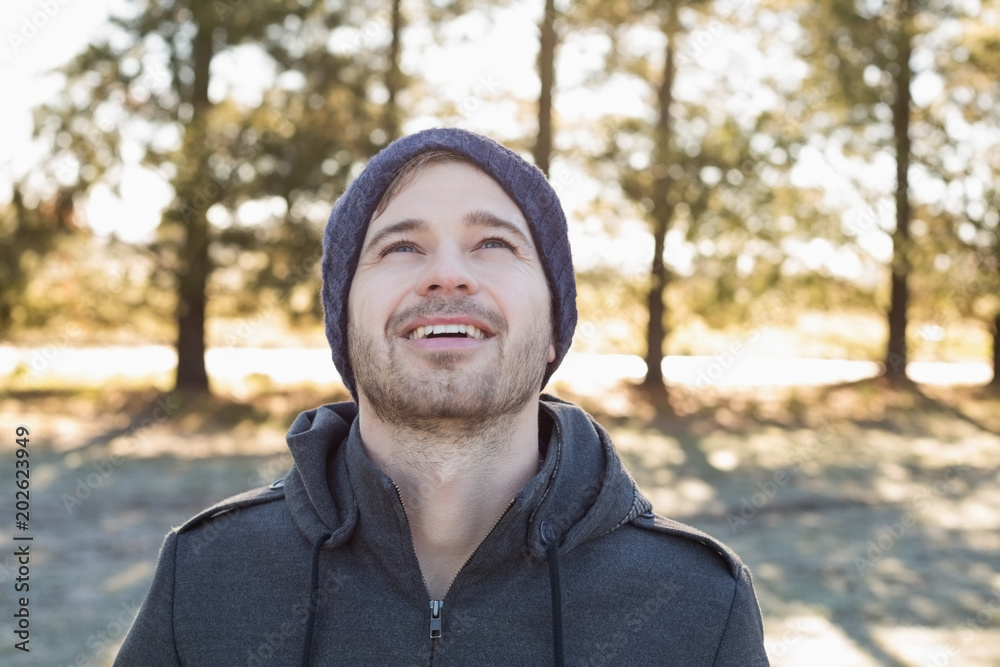 Smiling man in warm clothing looking up in forest Smiling man in warm clothing looking up in forest