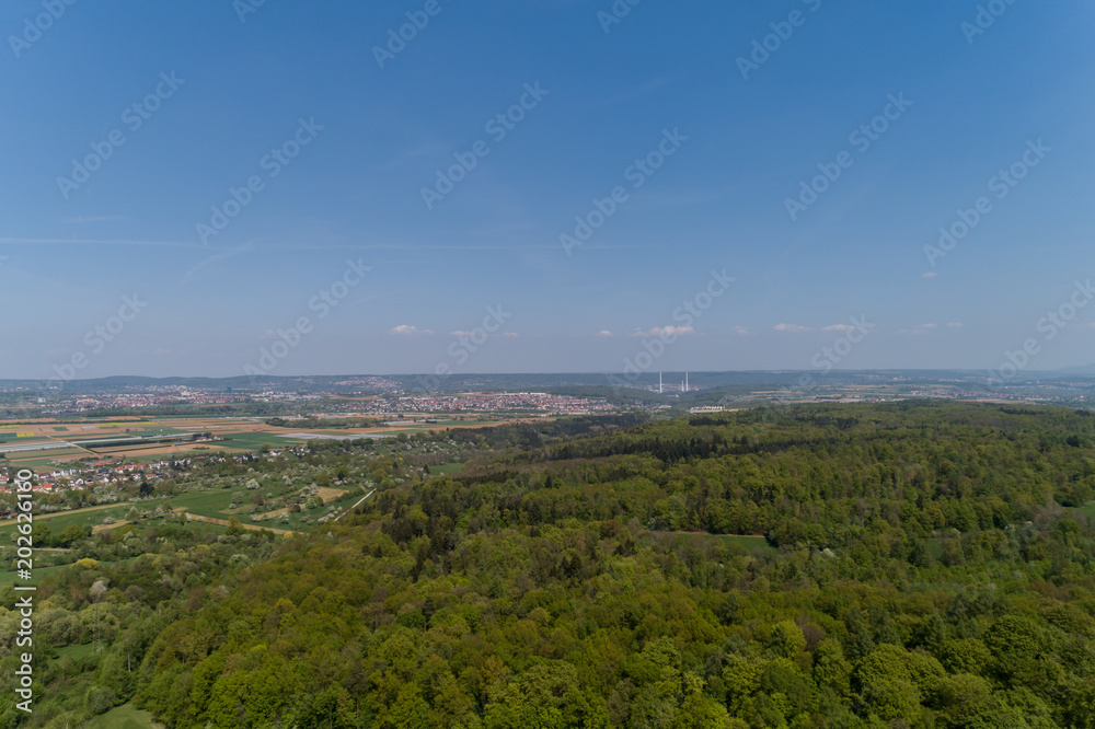 Luftbild mit Blick üner den Wald auf die Felderebene