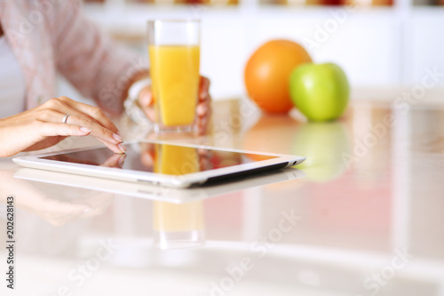 Young woman in the kitchen, using her ipad. Young woman