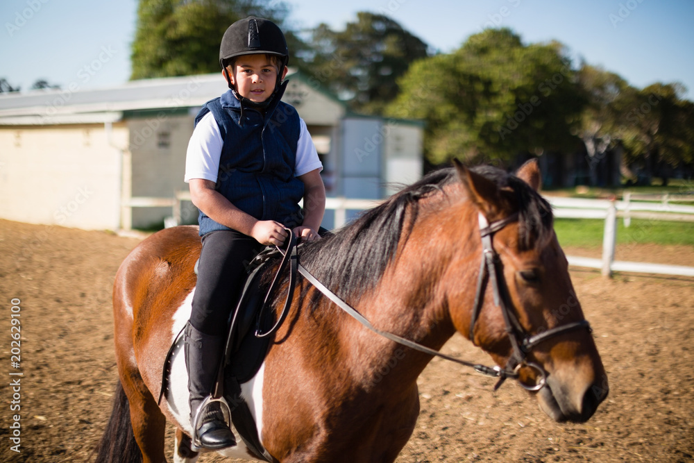 Boy riding a horse in the ranch Boy riding a horse in the ranch