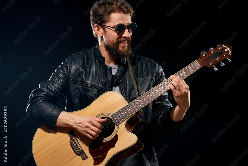 man with a guitar on a dark background looks away