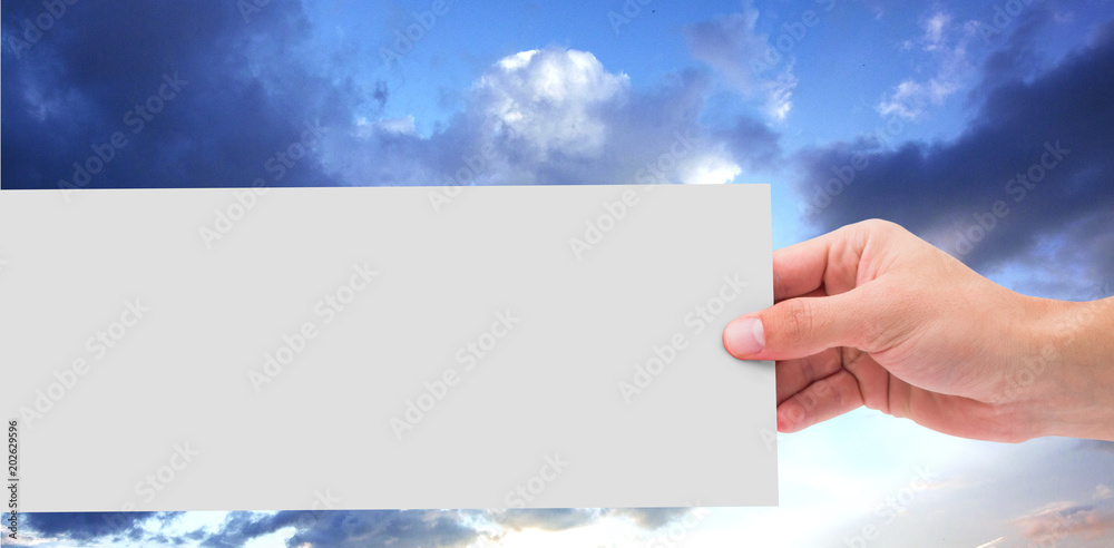 Hand showing card against blue and orange sky with clouds Hand showing card against blue and orange sky with clouds