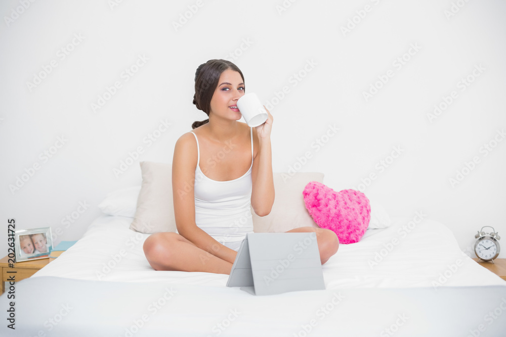 Pretty young brown haired model in white pajamas enjoying a coffee Pretty young brown haired model in white pajamas enjoying a coffee
