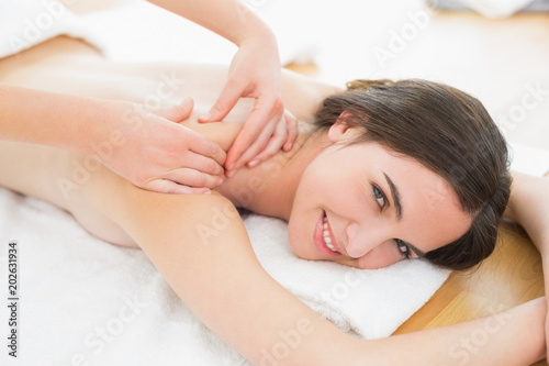 Smiling beautiful woman enjoying shoulder massage at beauty spa