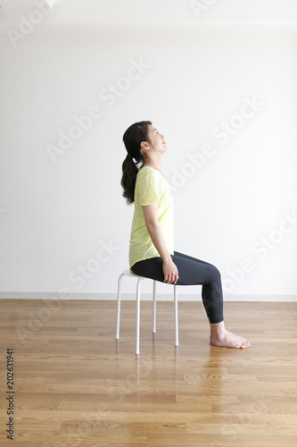 椅子を使ったストレッチ運動をする女性