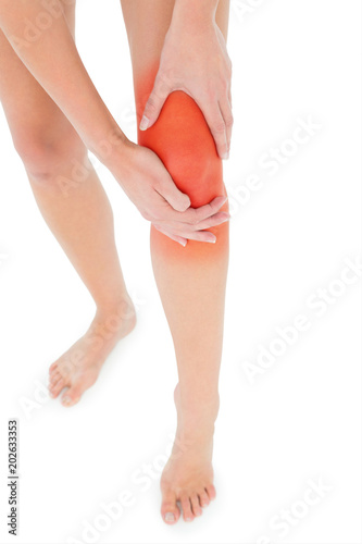 Closeup low section of a fit young woman with leg pain over white background © vectorfusionart