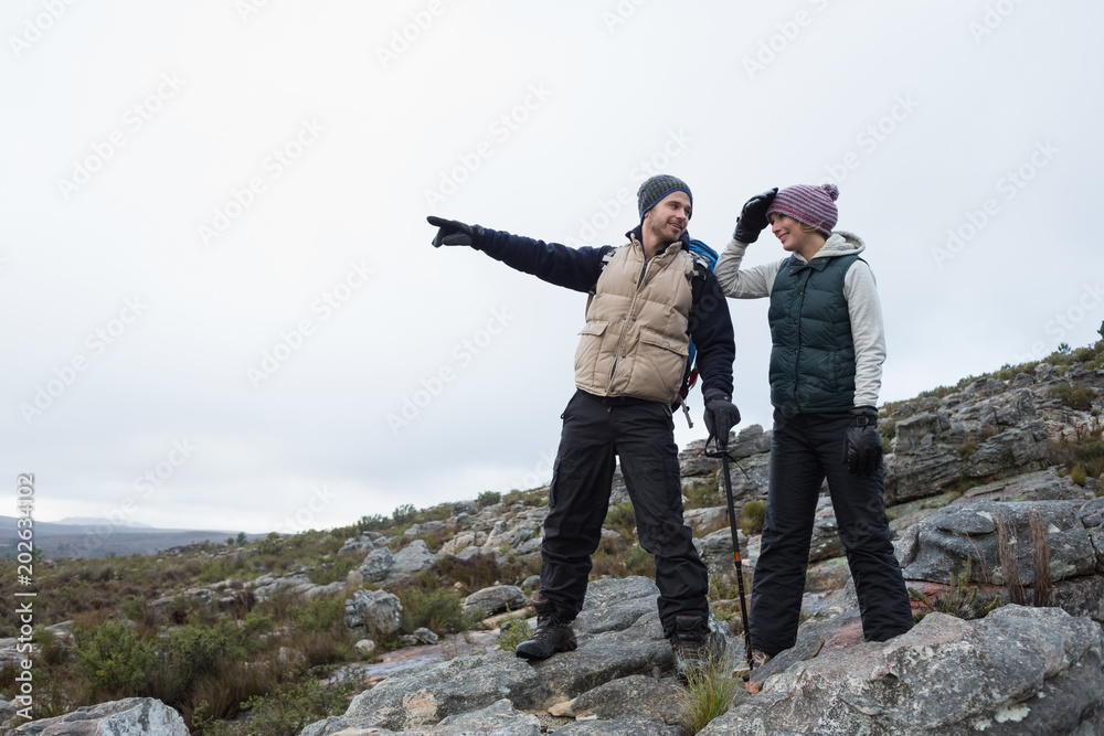 Couple standing on rocky landscape against clear sky