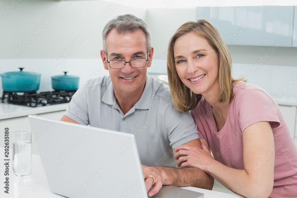 Portrait of a couple using laptop in kitchen Portrait of a couple using laptop in kitchen