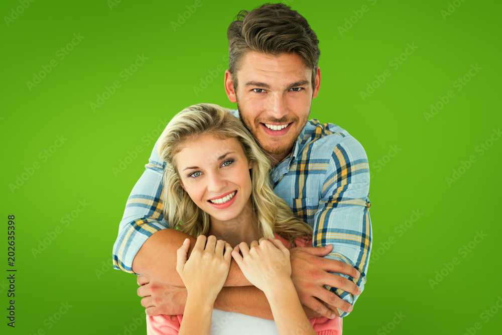 Attractive young couple smiling at camera against green vignette Attractive young couple smiling at camera against green vignette