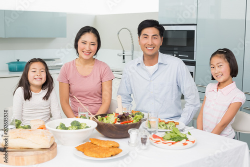 Happy family of four enjoying healthy meal in kitchen