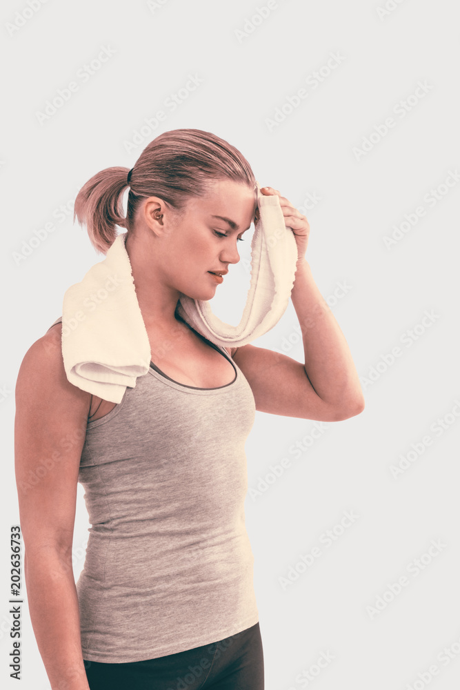Muscular woman wiping herself with towel against grey background Muscular woman wiping herself with towel against grey background