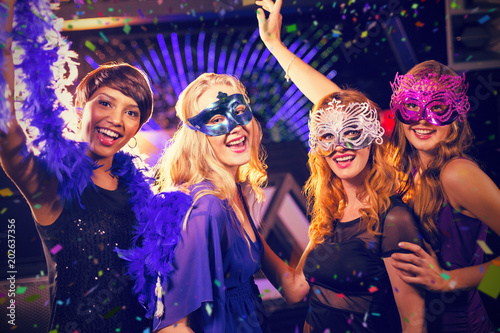 Group of smiling friends dancing on dance floor against flying colours