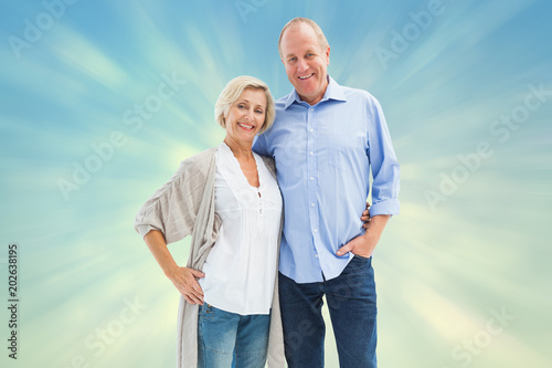 Happy mature couple hugging and smiling against blue abstract light spot design