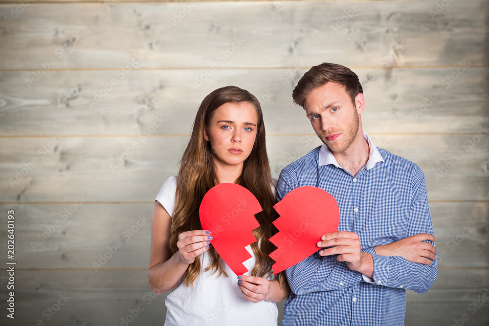 Couple holding broken heart against bleached wooden planks background