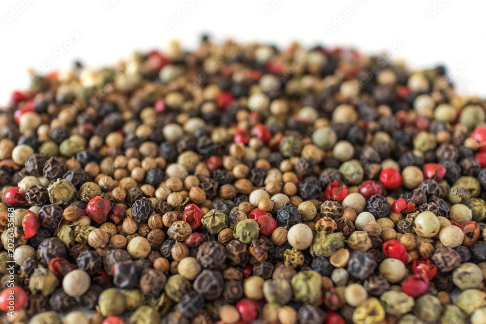 Pile of a mixture of black pepper, coriander, white pepper, pink, green pepper, peas, close-up, selective focus, side view, isolated on white background. Pile of a mixture of black pepper, coriander, white pepper, pink, green pepper, peas, close-up, selective focus, side view, isolated on white background.
