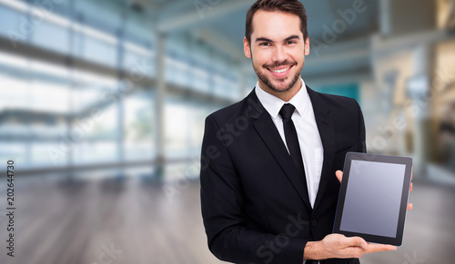 Smiling businessman showing his tablet pc against fitness studio