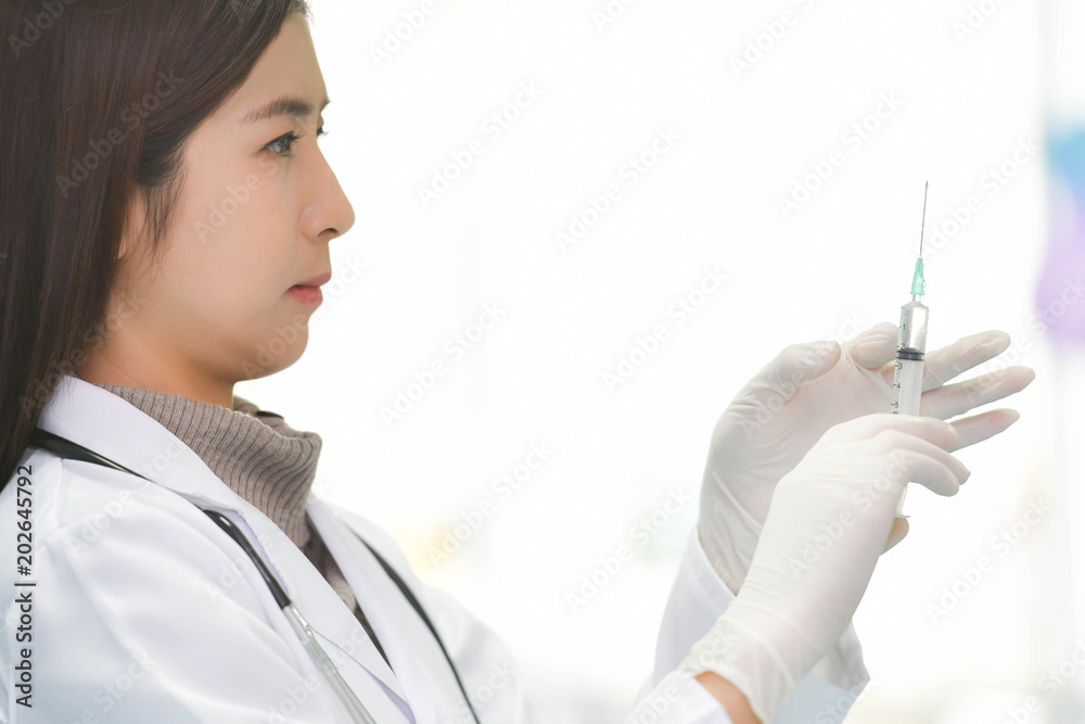 Smiling Asian medical doctor woman holding syringe with medicine in hospital with copy space Smiling Asian medical doctor woman holding syringe with medicine in hospital with copy space